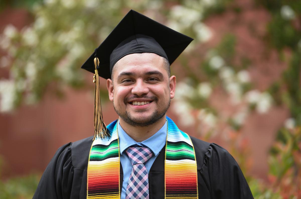 Male graduate wearing black cap and gown.