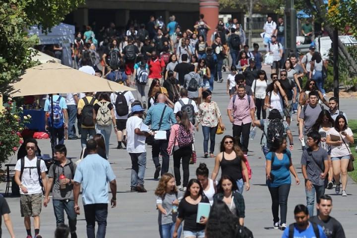 以图书馆为背景的大学走道. 学生们正在四处走动.